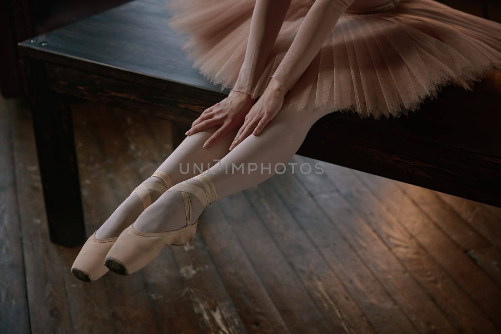 A poised young ballerina sits gracefully on stage, beautifully highlighting her elegant form and delicate ballet attire
