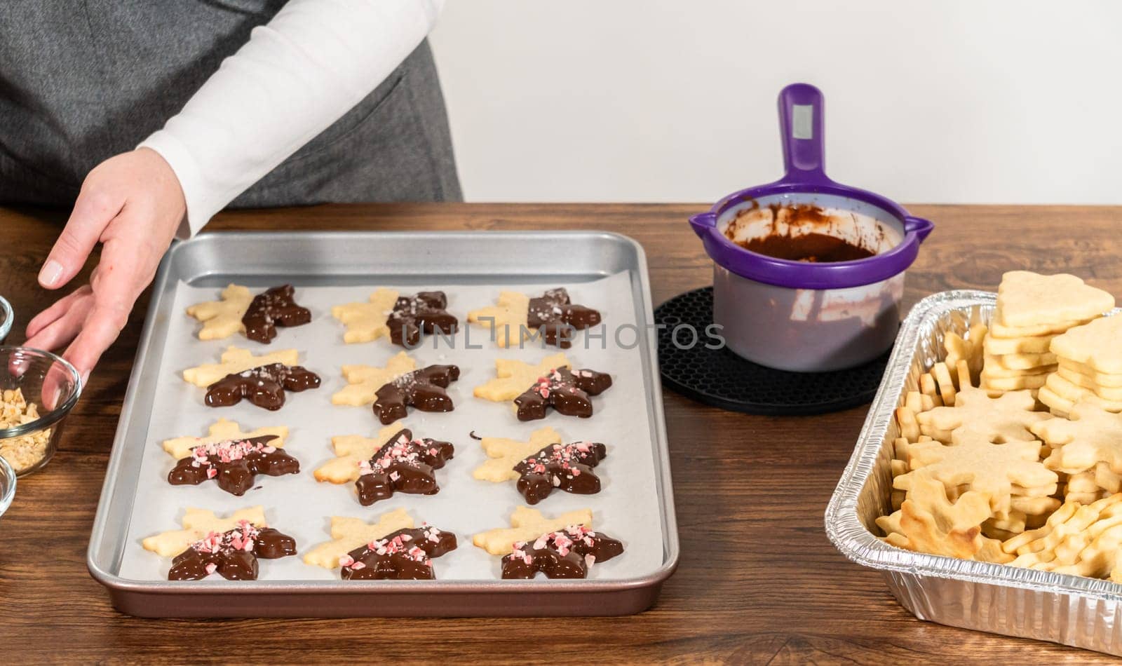 Preparing star-shaped cookies, half-dipped in chocolate, accented with peppermint chocolate chips for the holidays.