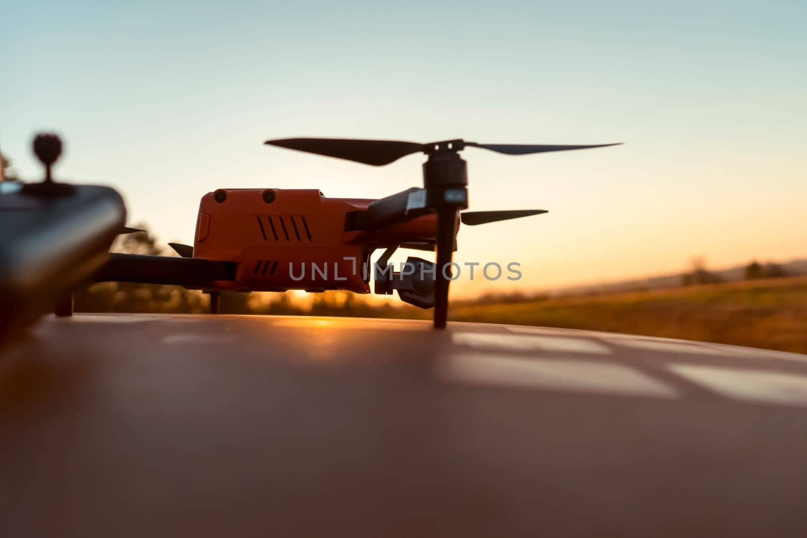 A drone and remote control against the sunset outdoors, in the rays of the sun. UAV technologies for monitoring territories, secret missions from the air, agricultural purposes and security.