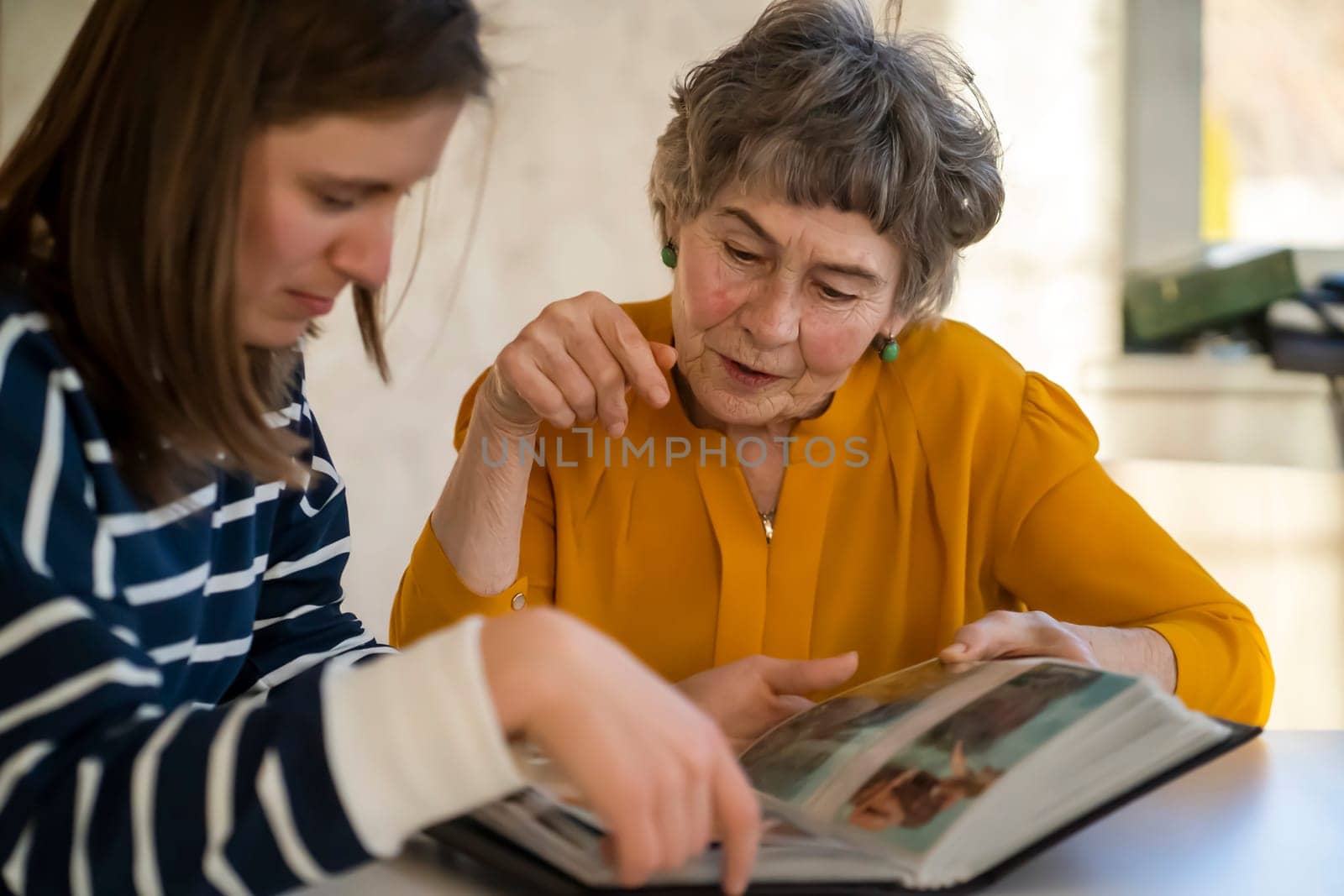 Grandmother and her young granddaughter spent great time together, family members look at photos from the youth of an elderly parent, through the pages of the album and recall funny stories from life.