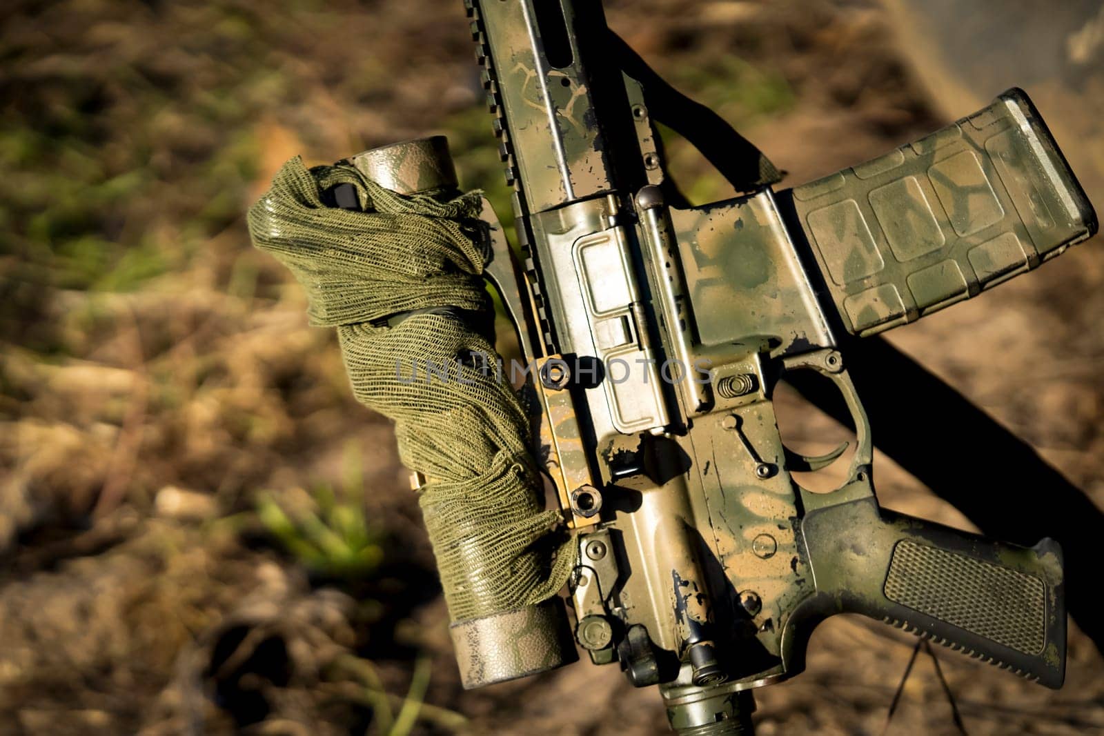 Hunting arch weapon, carbine with camouflage color, sight and camouflage net in the forest, against the background of the field during the hunt, closeup view.