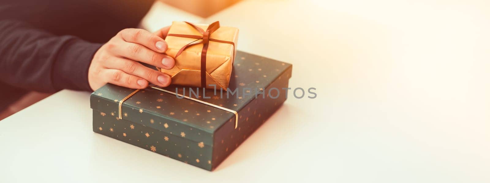 Male hands hold gifts in beautiful wrapping paper closeup view, a man prepares gifts for his loved one, relatives, friends and family for celebration the holiday.
