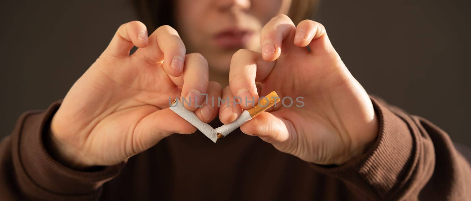 Young girl decisively breaks a cigarette in her hands, close-up view, a woman gets rid of nicotine addiction and chooses a healthy lifestyle, takes care of her beauty and health.