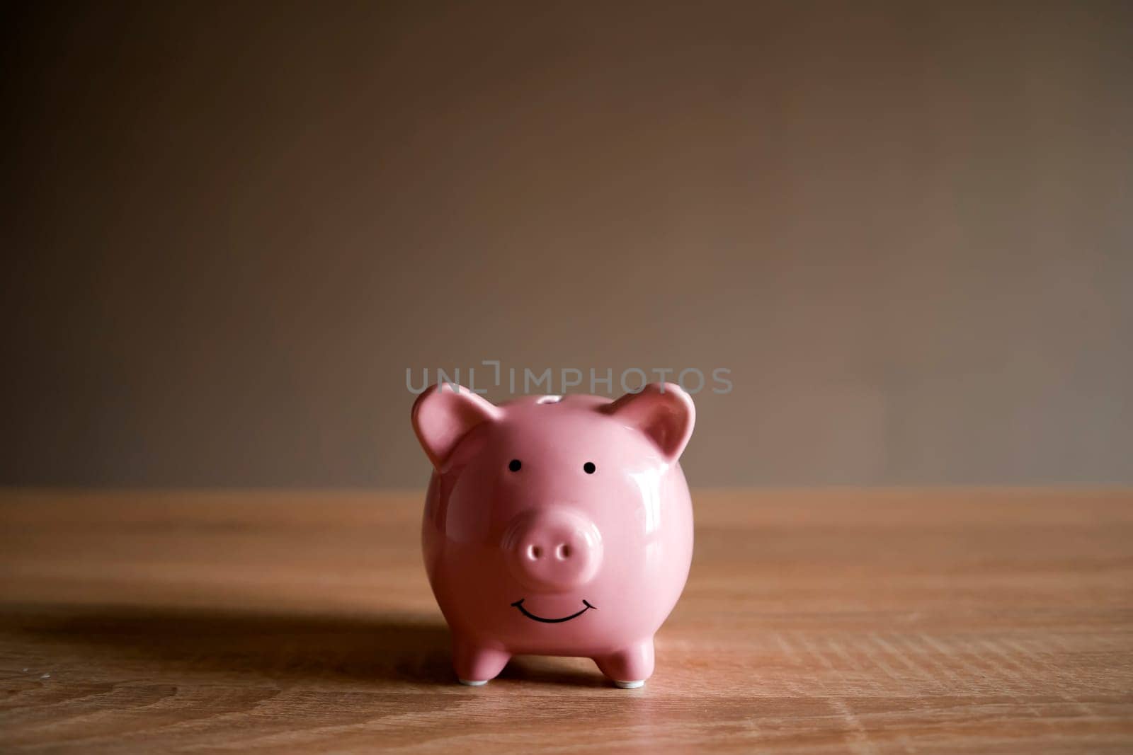 Piggy bank in the form of a smiling pink pig on the table to save wealth, savings and financial success, close-up view.
