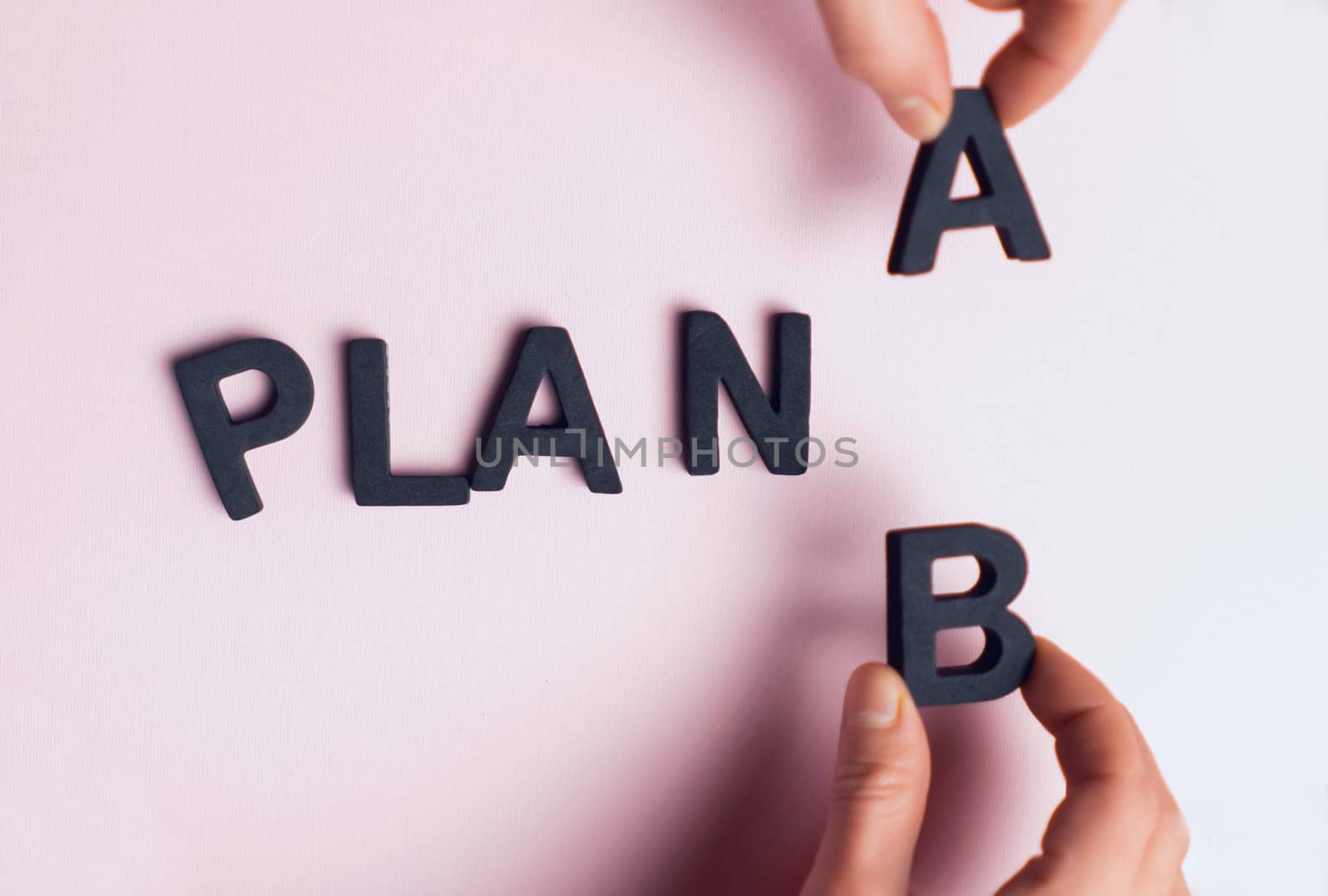 Top view of the scattered letters and the inscription, folded into the words "plan a", the hands of people replace the letter a with b. Creative concept about plan b, strategies and opportunities.