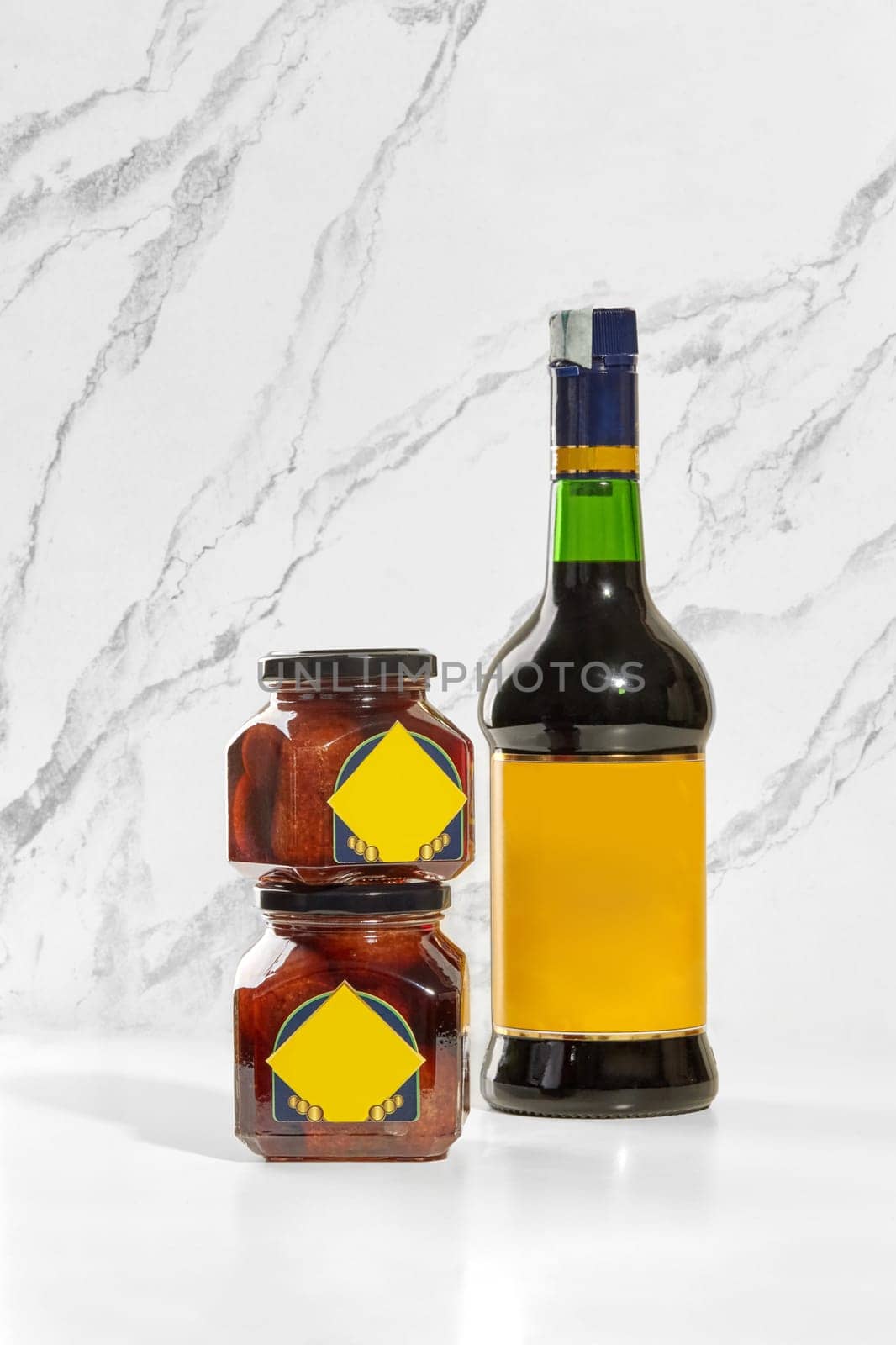 Two baba preserving jars and a borsci s. Marzano elixir bottle are displayed on a white marble surface