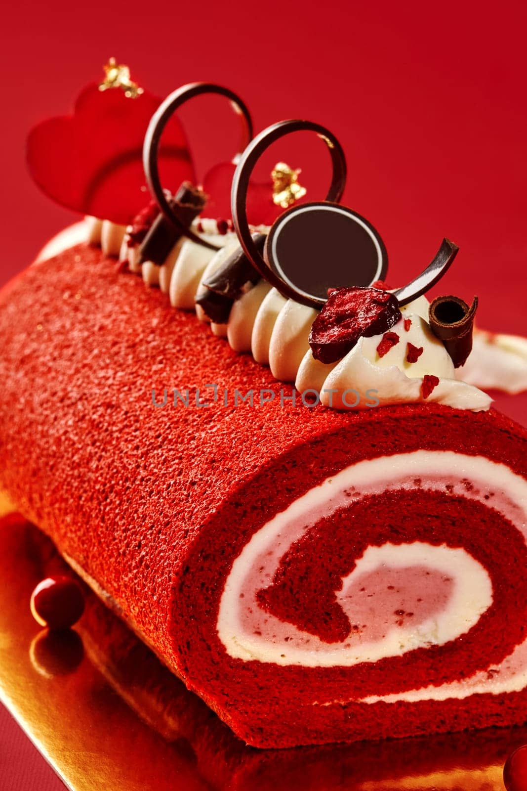 Delicious red velvet roll cake with whipped cream, chocolate curls, and dried cherries, perfect for valentine's day