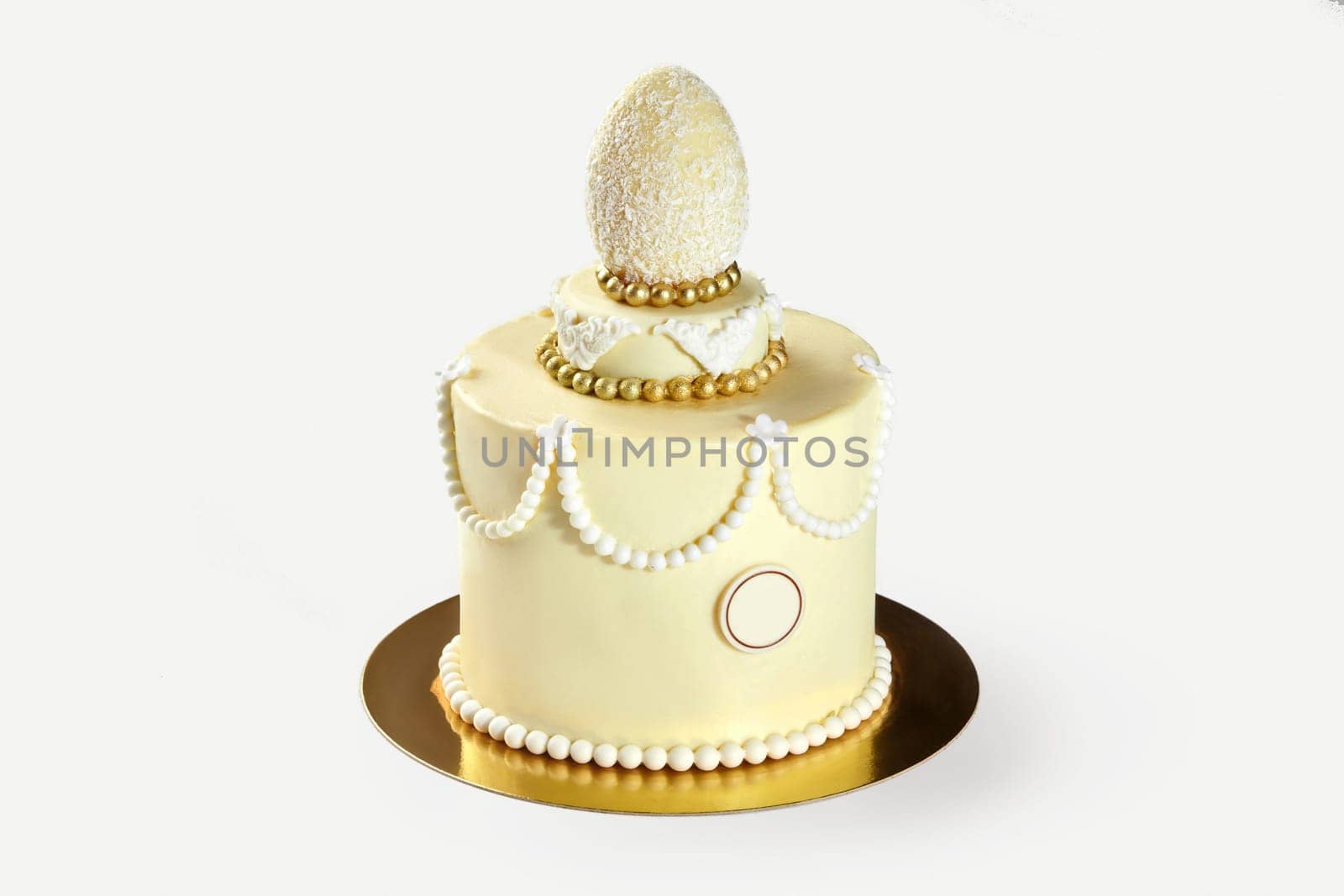 Small elegant easter cake decorated with white chocolate egg, pearls, and golden decorations