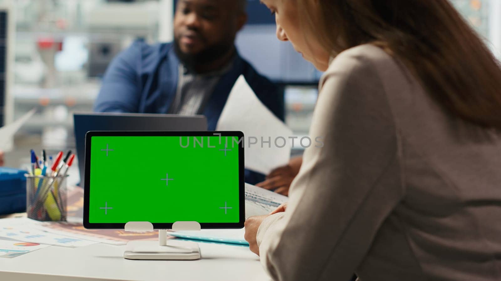 Shareholders in photovoltaics plant analyze market trends on isolated screen tablet to determine investment strategy. Managers look at data on mockup device, expanding factory production, camera B