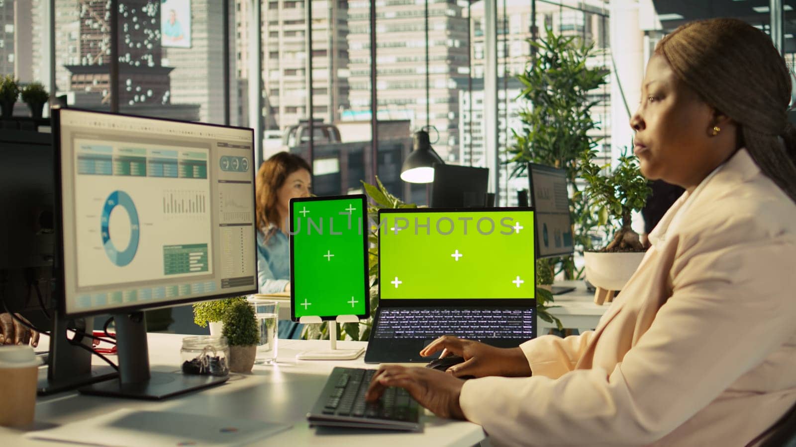 Isolated screen laptop and tablet on office desk next to employee editing documents on computer. Chroma key devices next to worker analyzing data charts, interpreting statistical information, camera B