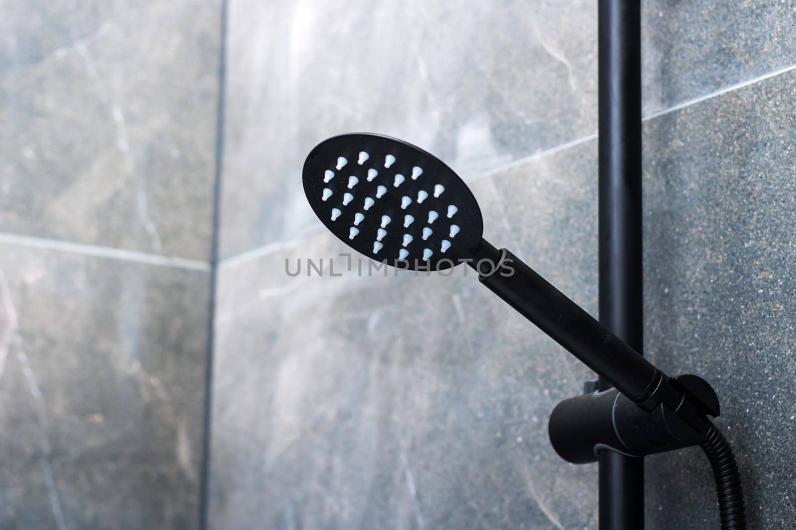A sleek black shower head featuring an appealing design of white dots adorning its surface, perfect for modern bathrooms