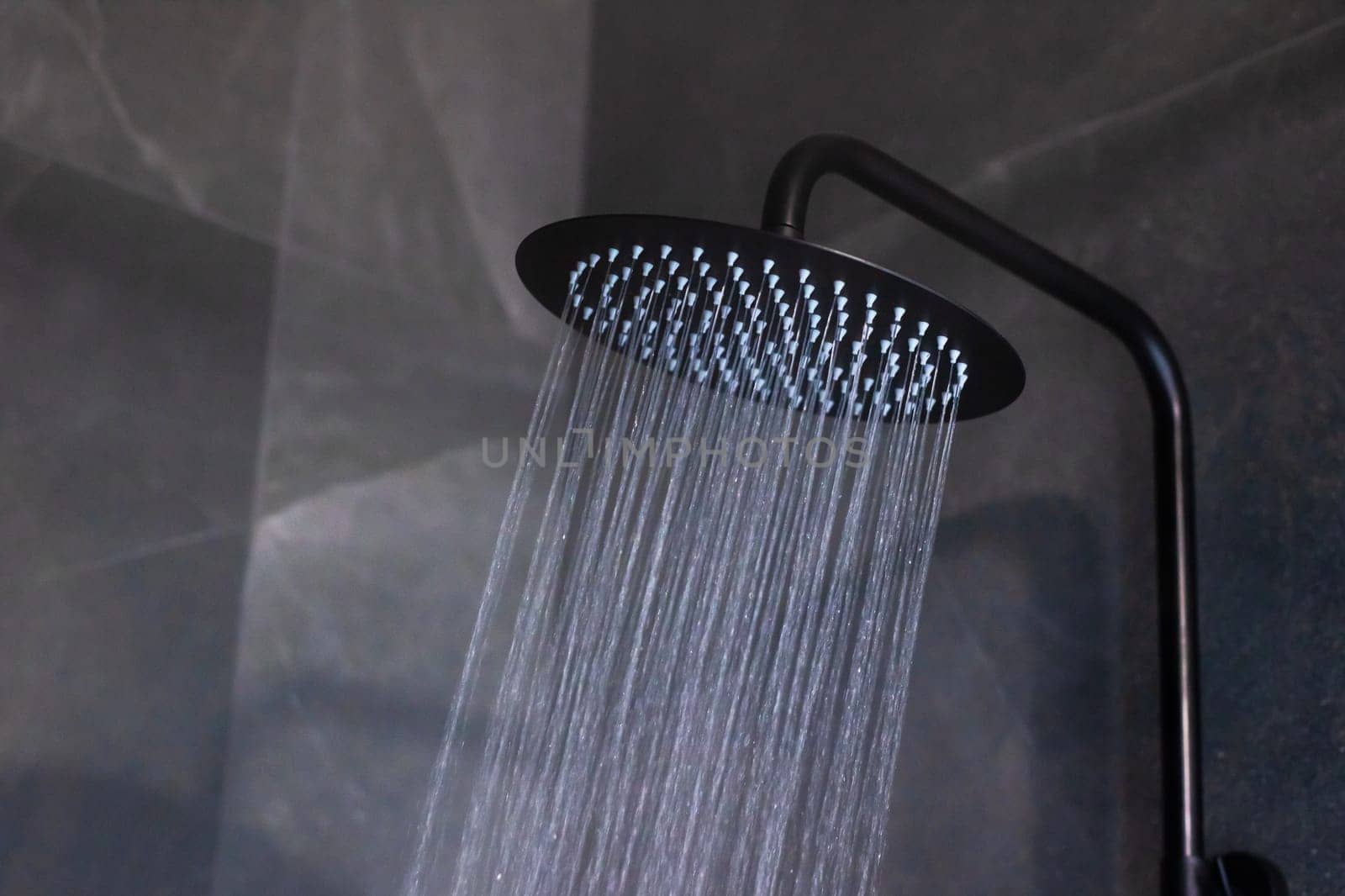 A sleek black shower head with water cascading elegantly from it, enhancing any modern bathroom design effortlessly