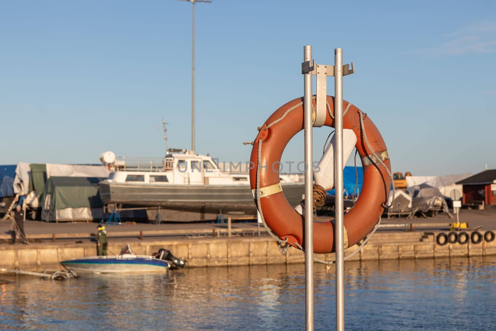 SOS nautical emergency concept. Lifebuoy, orange lifebelt put on vertical ready for using. Close up circle lifesaver buoy at Finnish marina