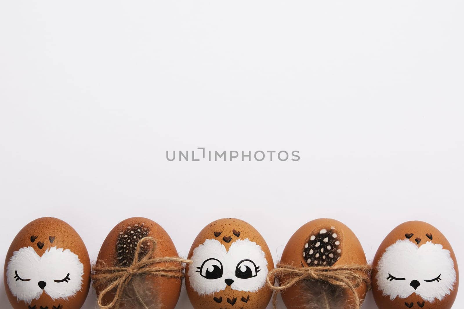 Funny owl family. Brown Easter eggs with painted faces. Space for your text.