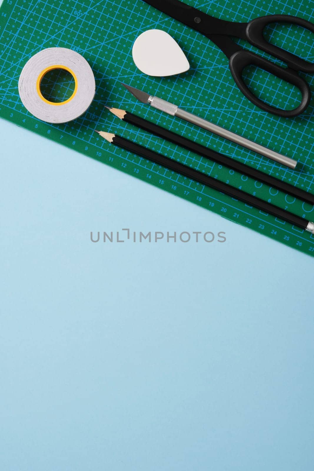 Supplies for paper art hobby: scissors, craft knife, pencil, eraser, cutting mat. Space for your text. Paper crafts work table flatlay.