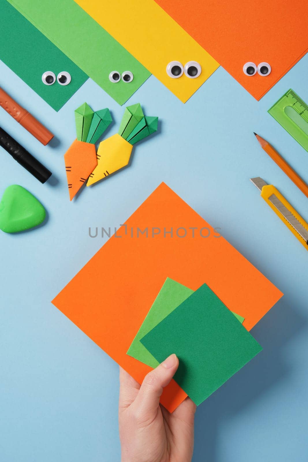 Making origami carrot. DIY project. Take a square sheet of orange color and two small squares of green color.