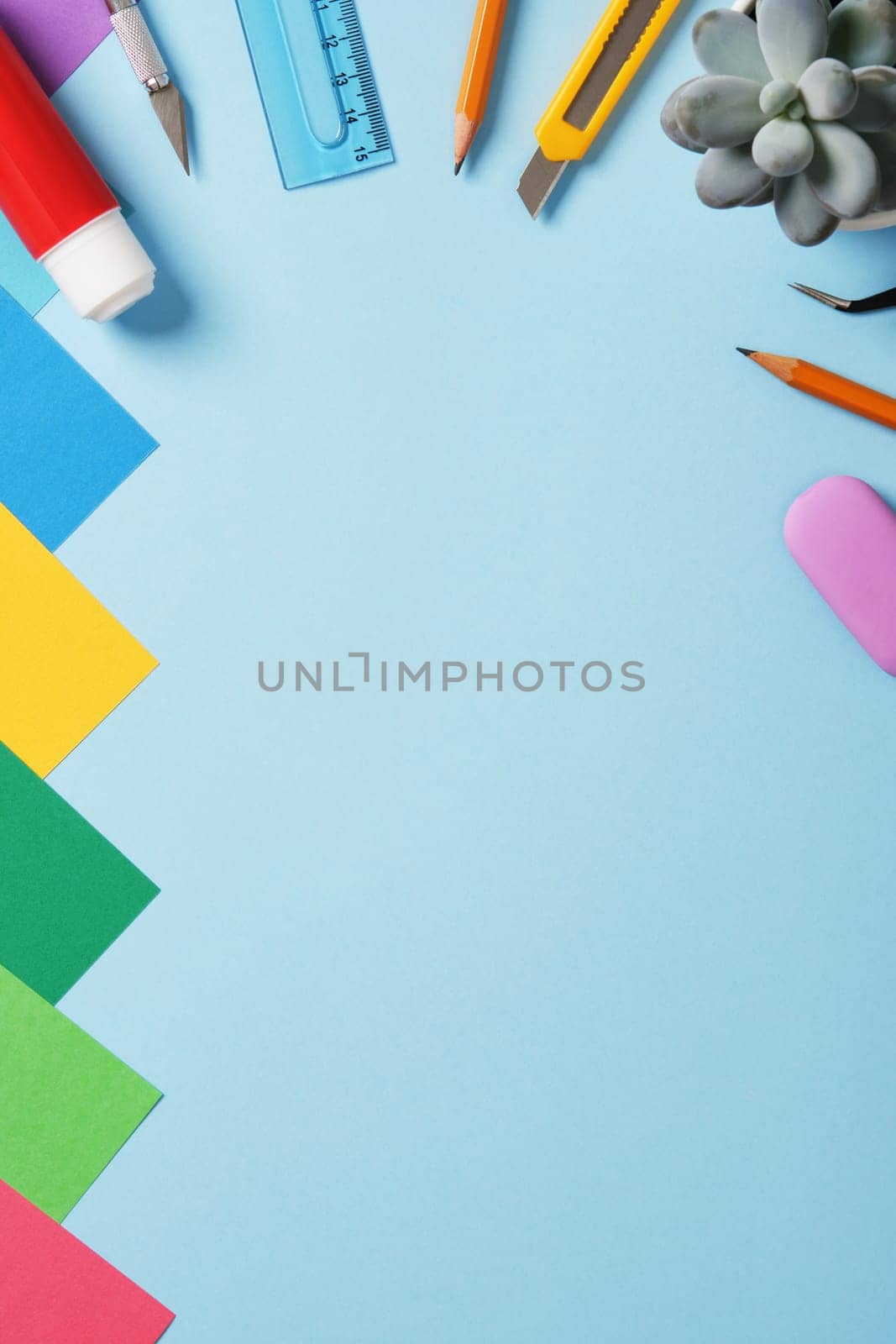 Supplies for paper art hobby: scissors, craft knife, pencil, eraser, colored paper. Space for your text. Paper crafts work table flatlay.