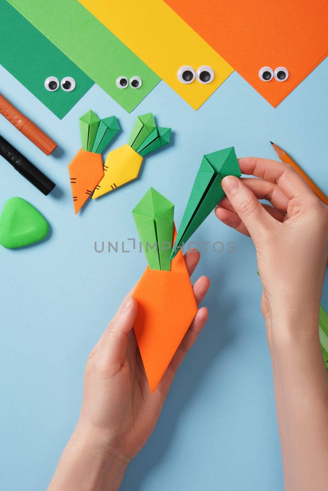Making origami carrot. DIY project. Insert the resulting leaves into the orange part of the carrot.