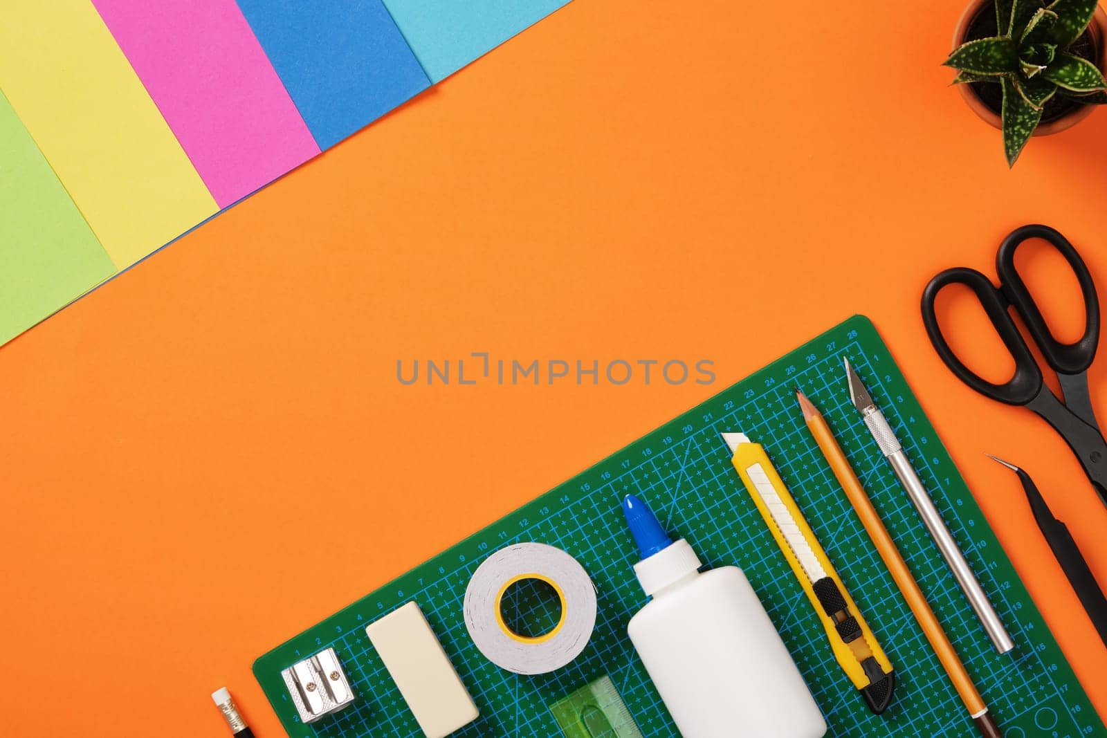 Top view of the paper crafts work table. Scissors, craft knife, pencil, tweezers, eraser, cutting mat, paper. Place for your text.