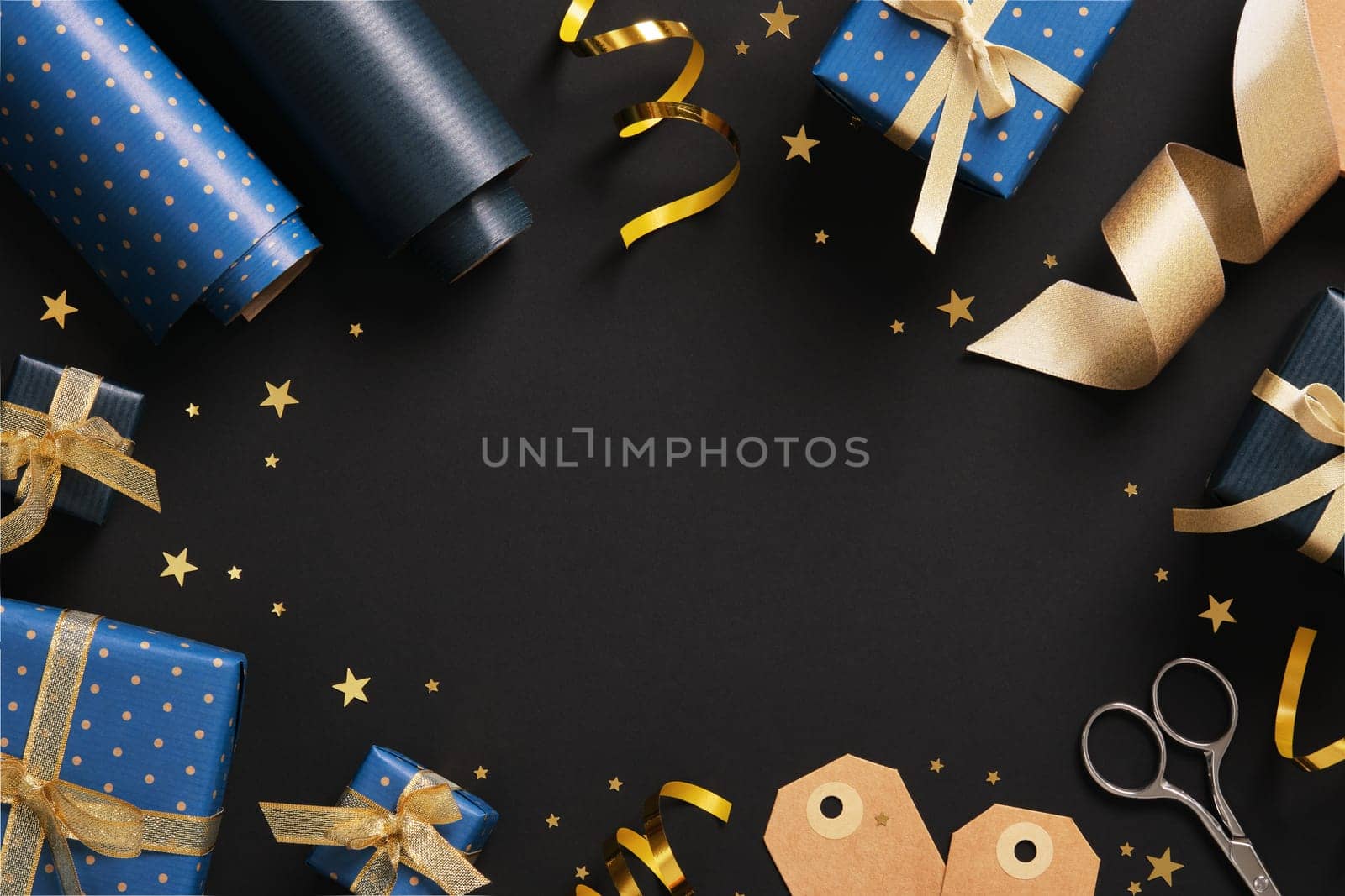 Horizontal frame made of gift wrapping materials. Blue wrapping paper, tags and gold colored ribbon. Space for your text.