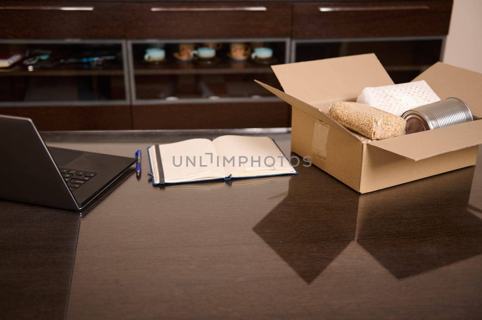 Desk setup featuring a laptop, notebook, and delivery box with items. Perfect for concepts of business, online retail, supply chain, productivity, and remote work environments.