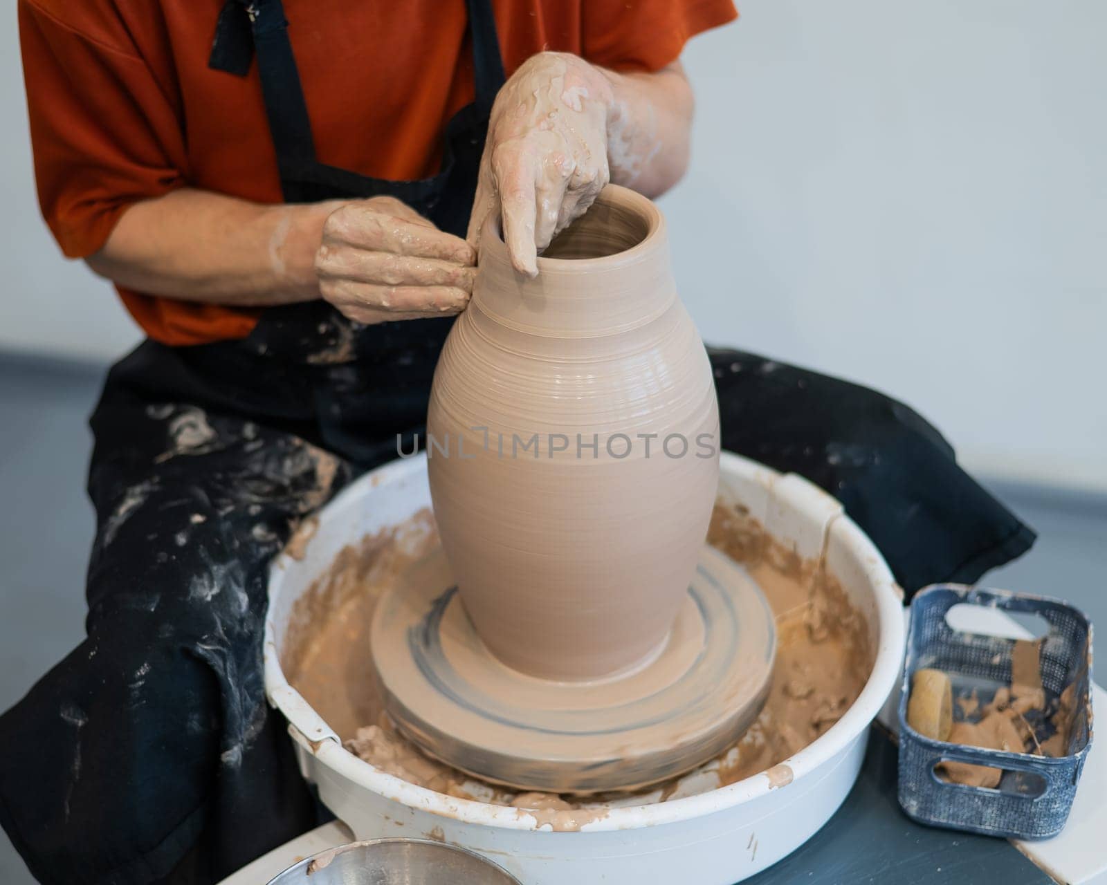 Close-up of a potter's hands making a ceramic vase on a potter's wheel
