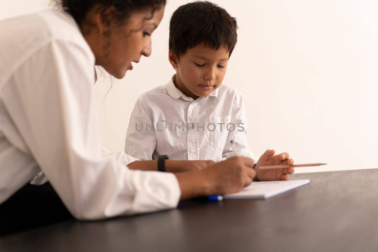Teacher assisting a young student with his writing skills, fostering education and development