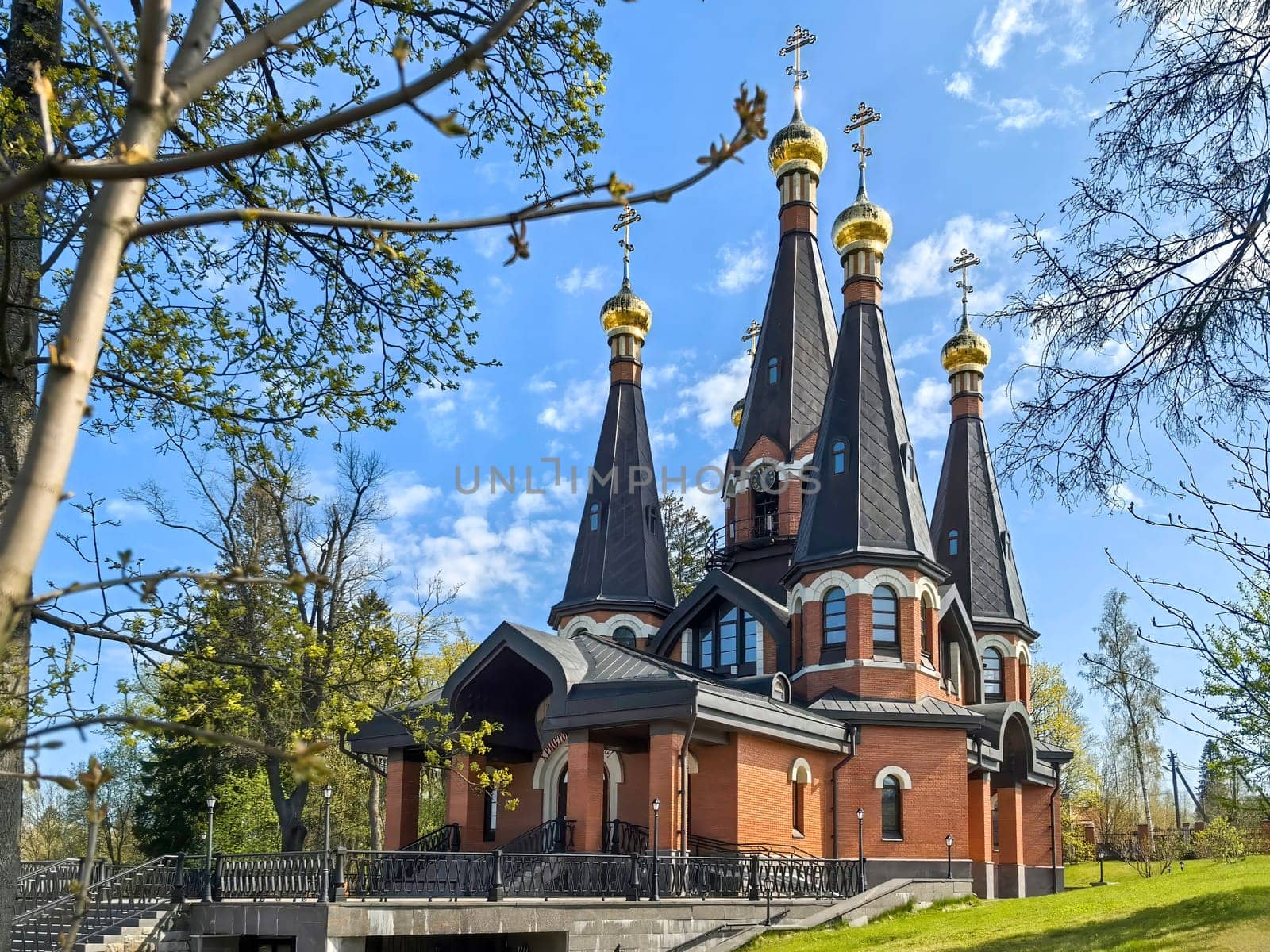 Yukki, Leningrad Oblast, Russia - May 28, 2025. Church of St. John the Baptist in Yukki showcases its striking architecture with golden domes under a blue sky.