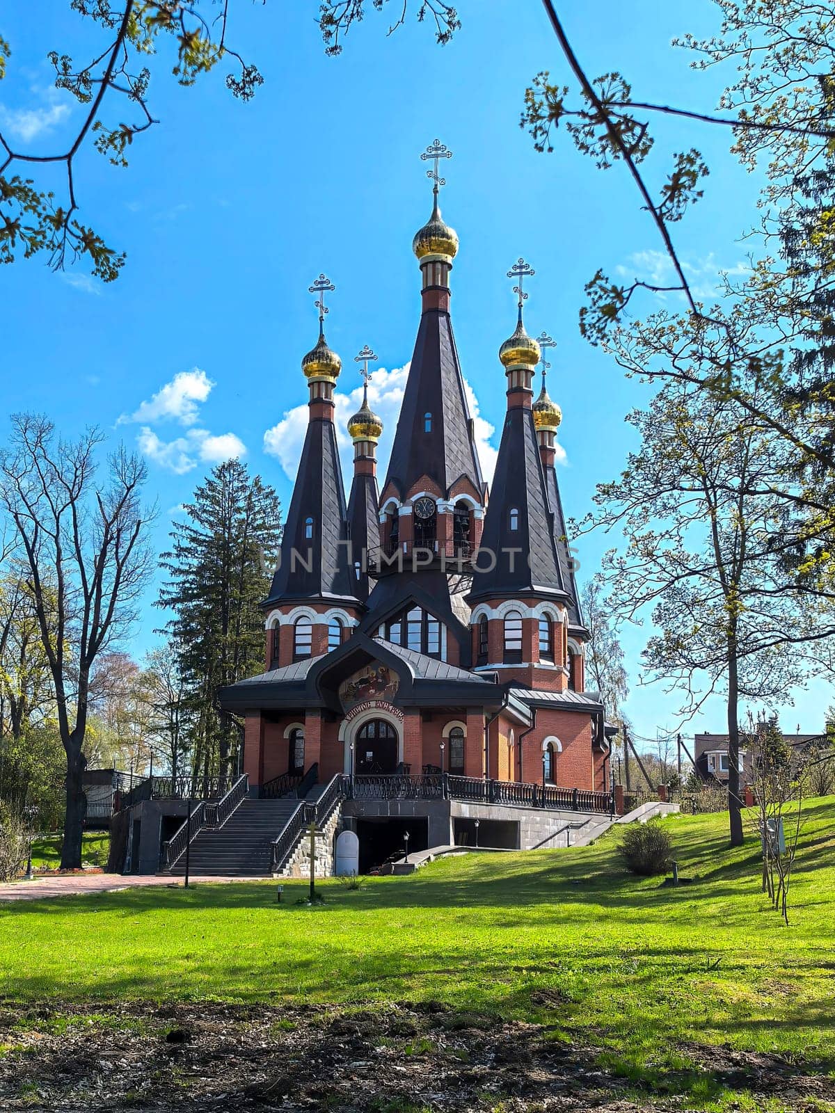 Yukki, Leningrad Oblast, Russia - May 28, 2025. Church of St. John the Baptist in Yukki showcases its striking architecture with golden domes under a blue sky.