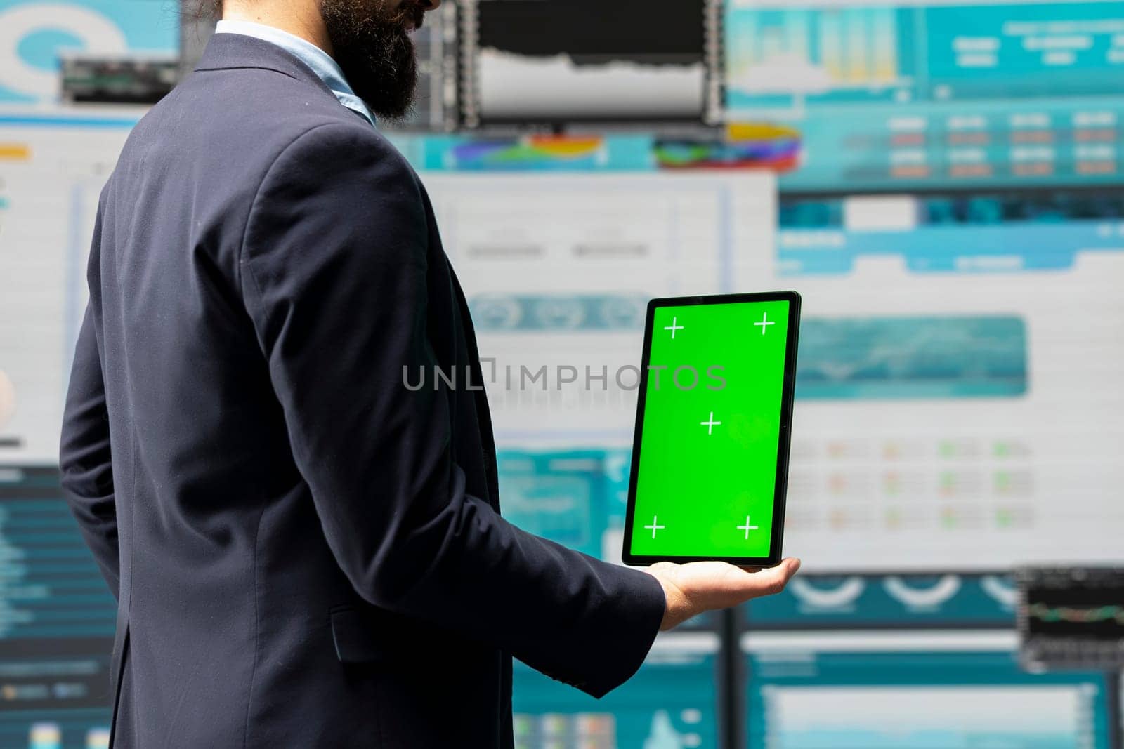 Male administrator uses green screen tablet to explore new growth strategy with insight and analytics in a digital workspace. Representing modern business intelligence and productivity.
