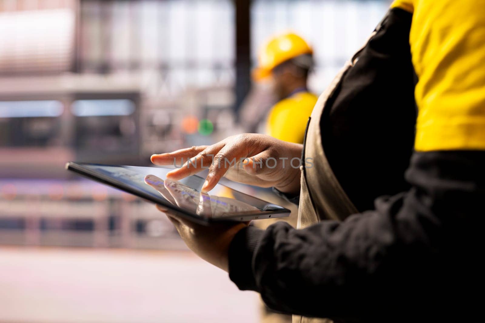 Closeup of professional using tablet in high tech factory, symbolizing industry 4.0, digital automation and real time production monitoring. African american engineer handling robotic arm maintenance.