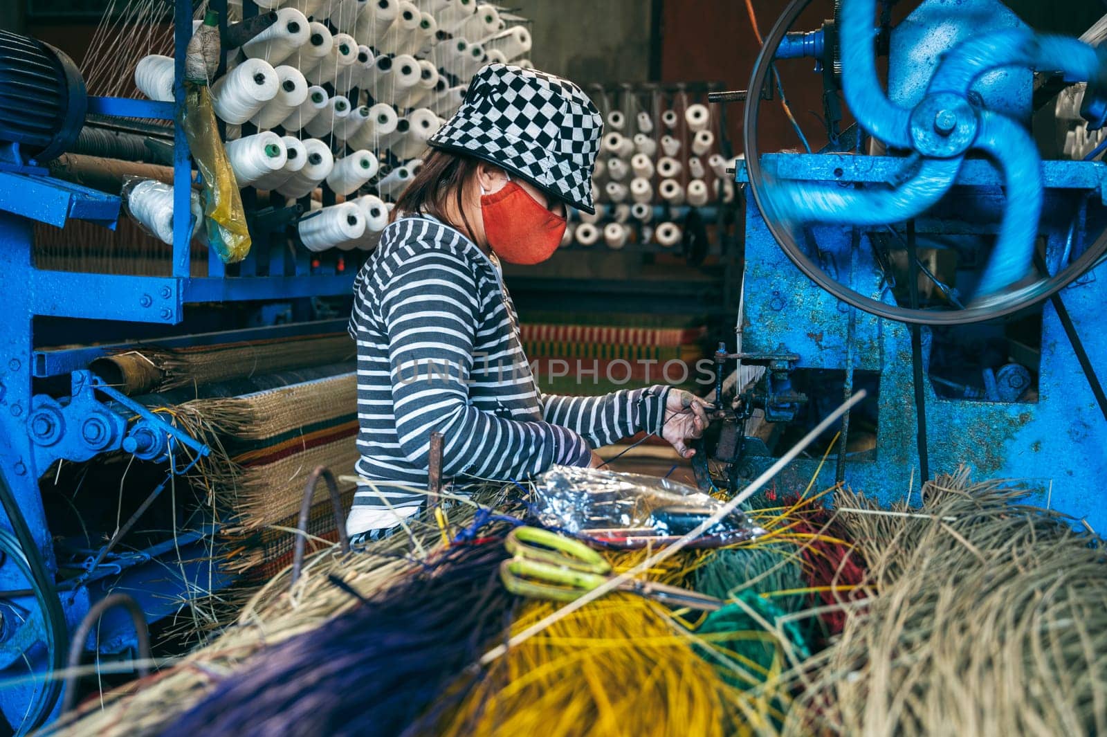 Vietnamese female weaver works on a loom in workshop at a factory producing traditional woven reed mats in Vietnam in Asia