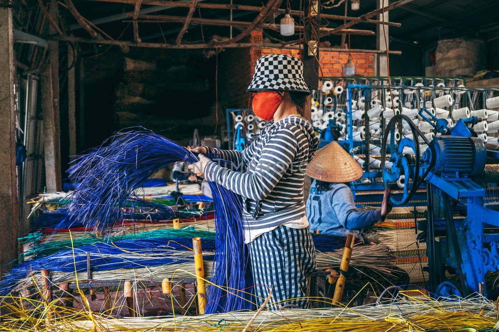 Vietnamese woman works at loom in factory for the production of woven reed mats in Vietnam. An Cu, Tuy An, Phu Yen province, Vietnam - April 14, 2025