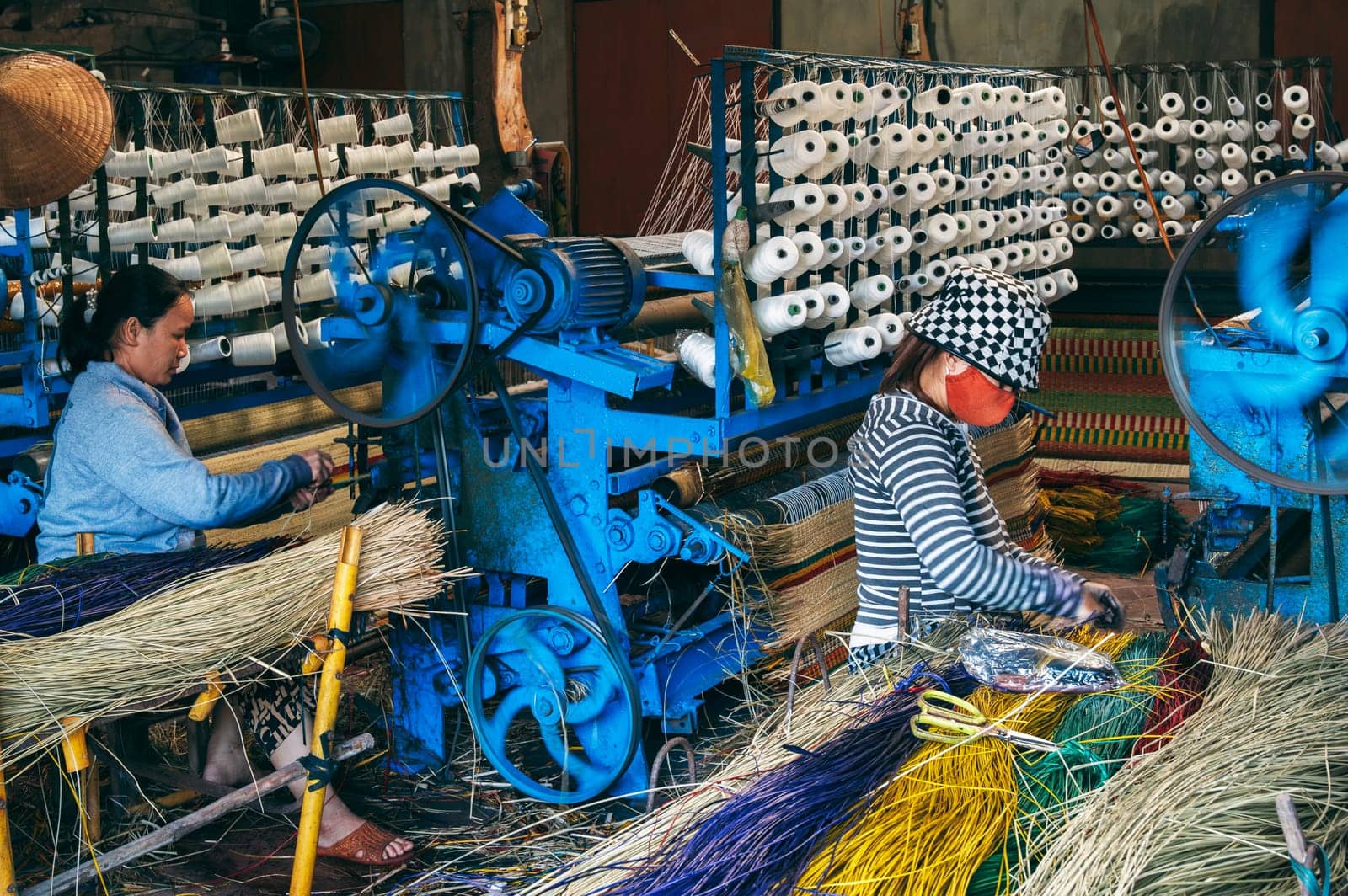 Vietnamese women weavers works at a looms weaving machines in a workshop at factory for the production of woven reed mats in Vietnam in Asia. An Cu, Tuy An, Phu Yen province, Vietnam - April 14, 2025