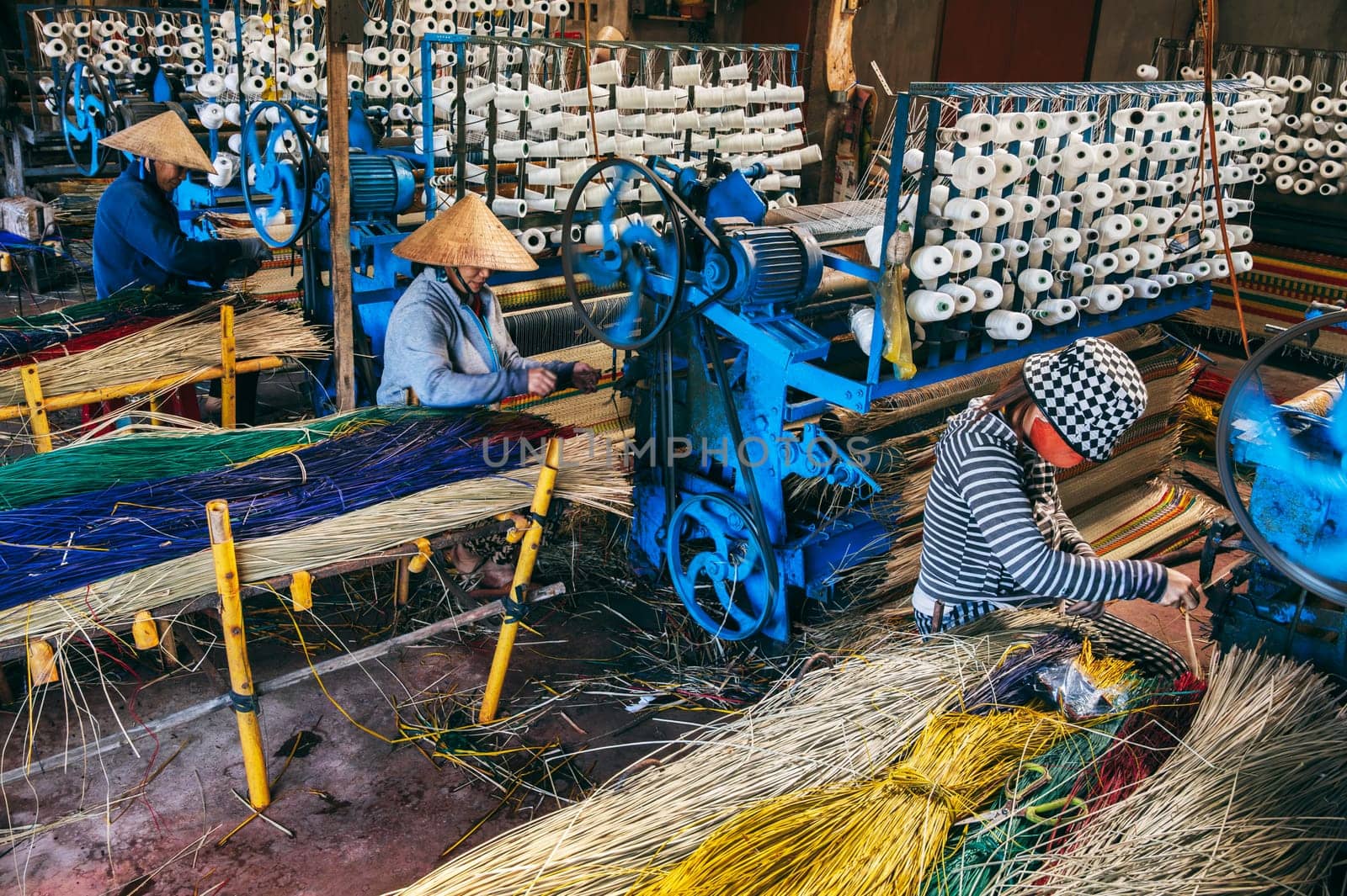 Vietnamese women weavers works at a looms weaving machines in a workshop at factory for the production of woven reed mats in Vietnam in Asia. An Cu, Tuy An, Phu Yen province, Vietnam - April 14, 2025