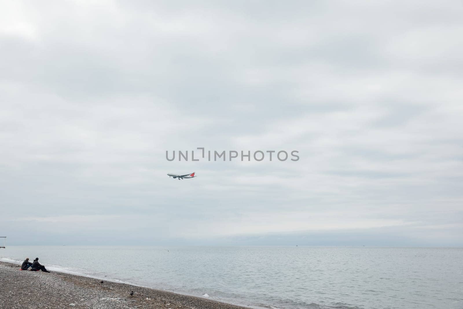 People on the beach watching a passenger plane