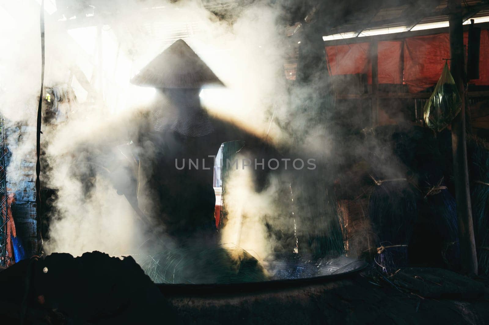Vietnamese woman worker works in reed dyeing workshop at wicker mat factory in village in Vietnam