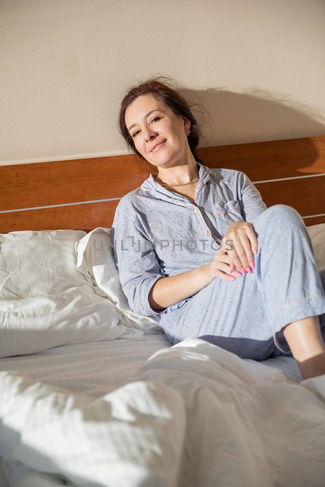 Brunette in pajamas woke up in the morning in the bedroom on the bed smiling