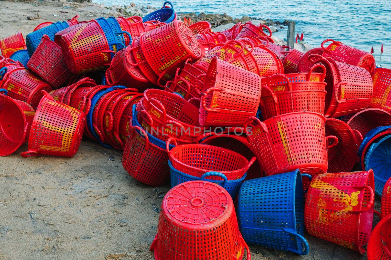 A lot of empty plastic baskets for catching fish are lying in pile on the beach at a fish market in Vietnam. Xuan Hai, Song Cau, Phu Yen province, Vietnam - April 12, 2025