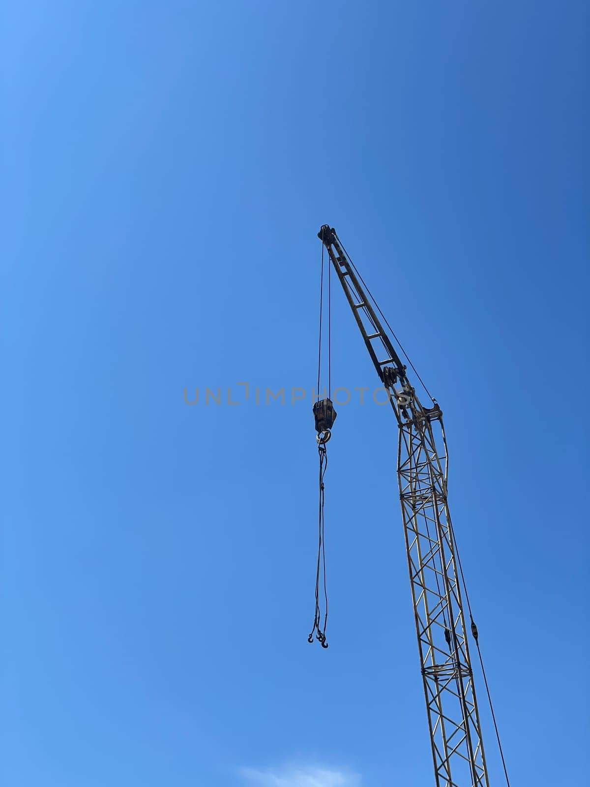 Metal construction crane at construction site with blue sky background