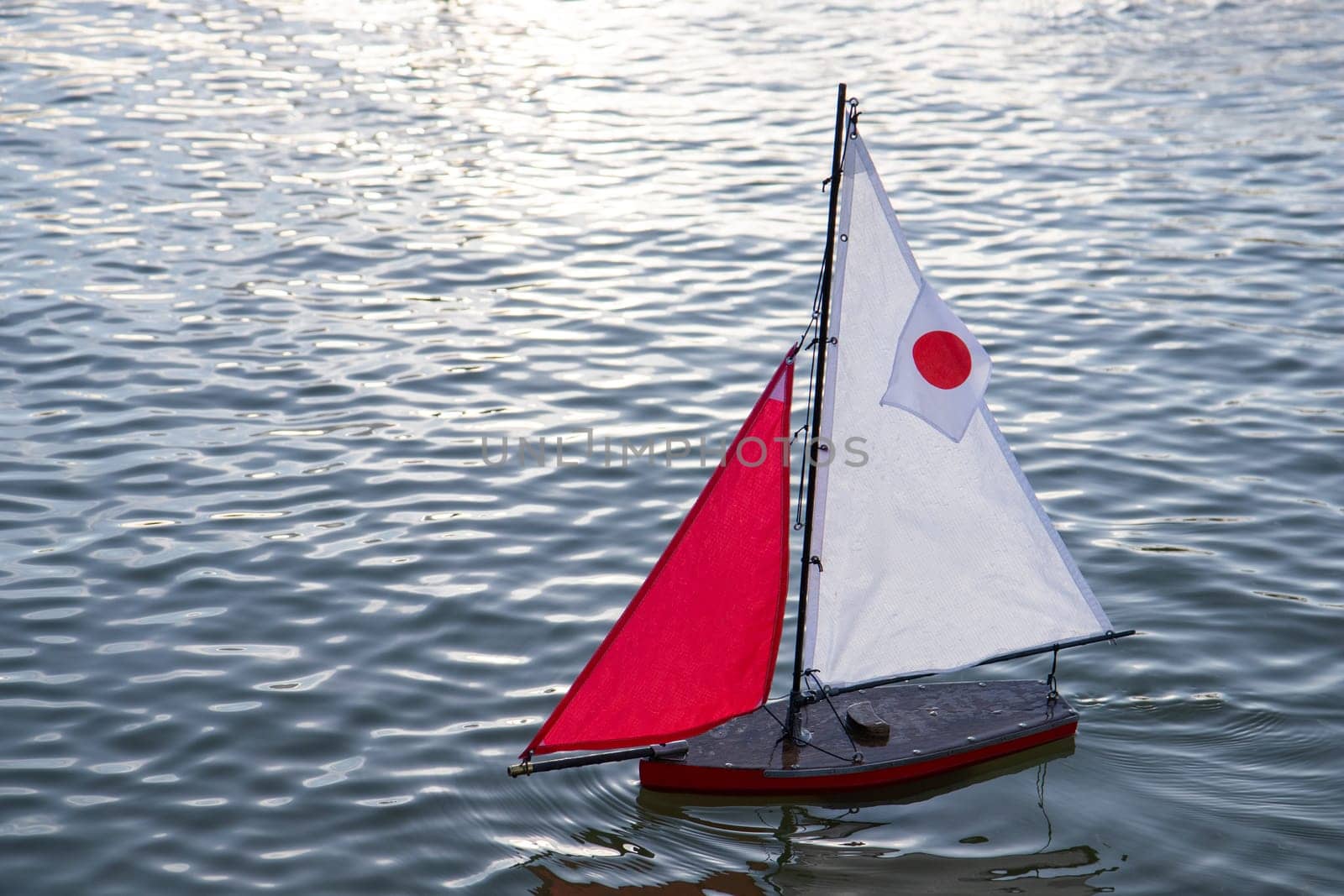 A small toy sailboat floats gently on the surface of calm water in the Luxembourg Garden Jardin du Luxembourg, Paris, France