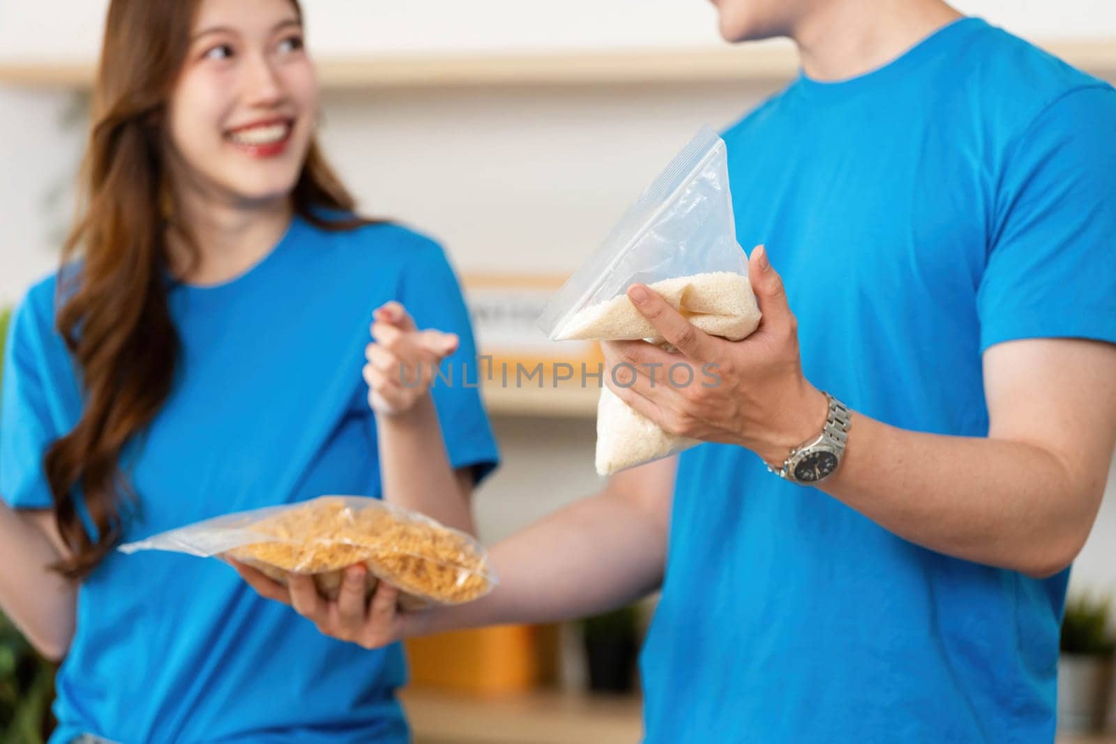 Two volunteers happily sharing food items, demonstrating teamwork and commitment to community welfare.