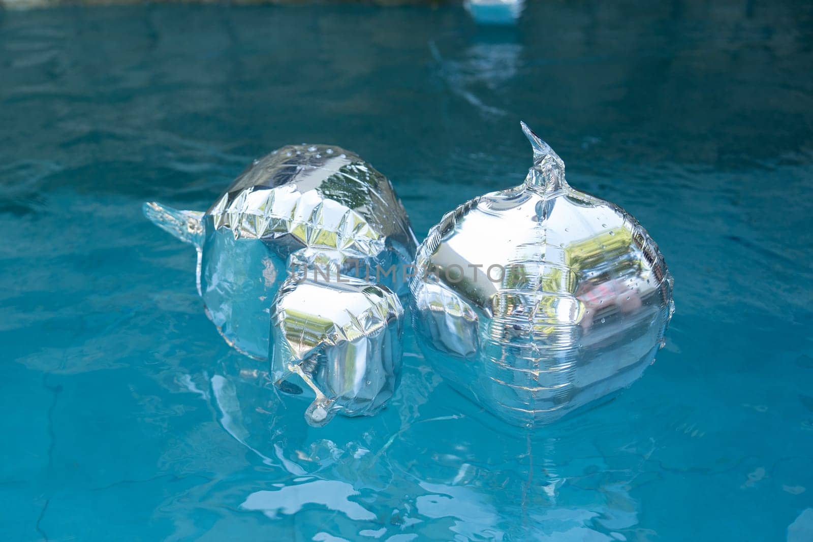 Silver balloons float in pools for a birthday party decorations