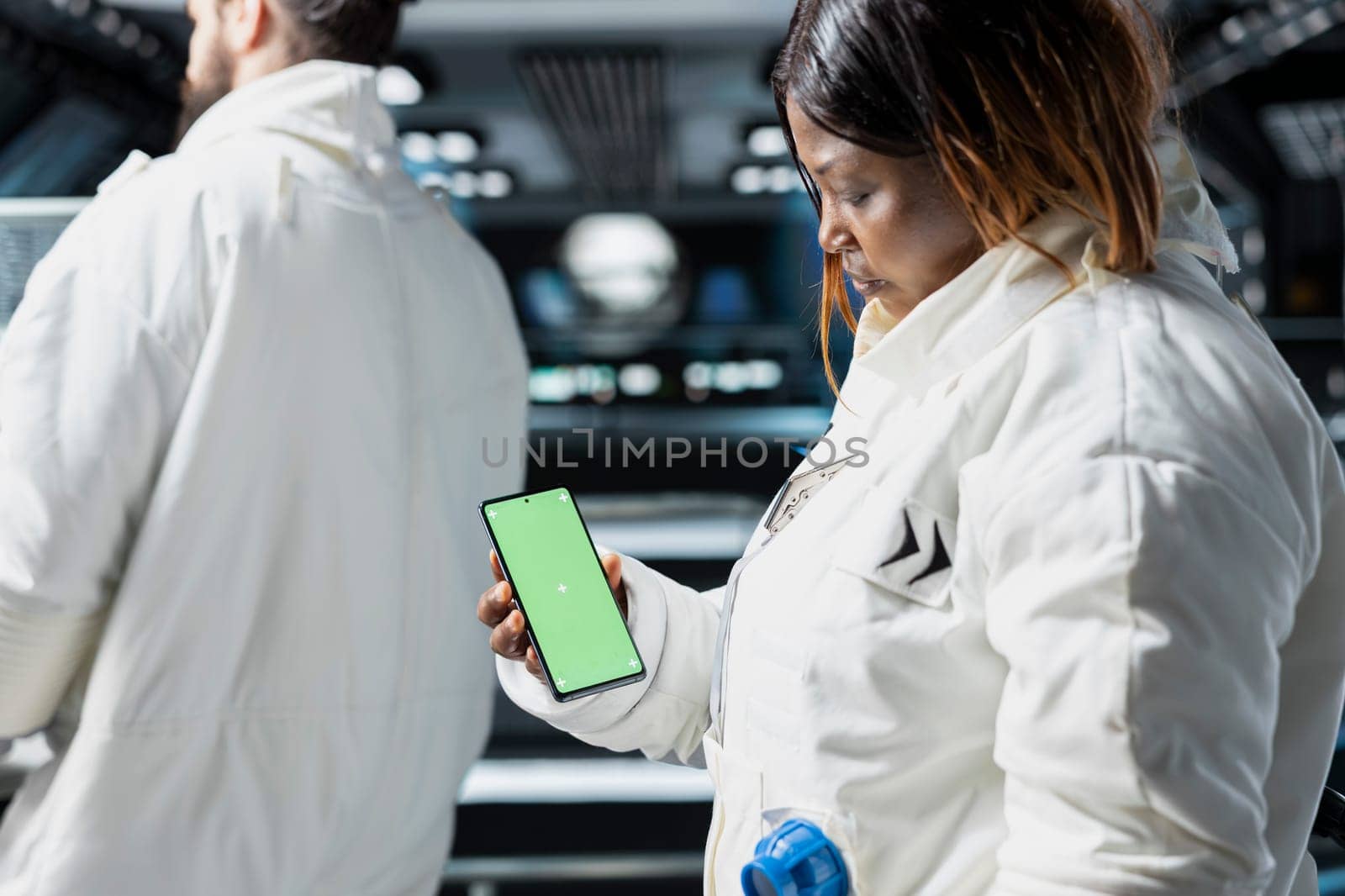 Scientists conduct visual data tests using chroma key smartphone aboard advanced starship during spaceflight. Cosmonauts perform orbital experiments, relying on isolated screen phone for analysis