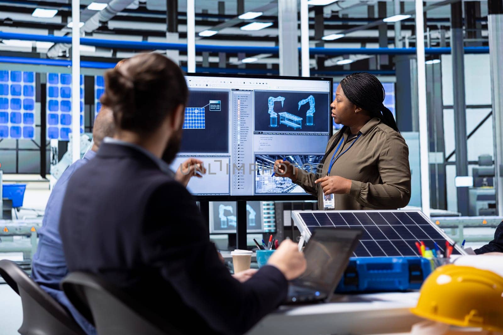 Shareholders collaborate on renewable energy investments, looking at data on display. Photovoltaics facility management team looking at manufacturing equipment specs on monitor, doing brainstorming