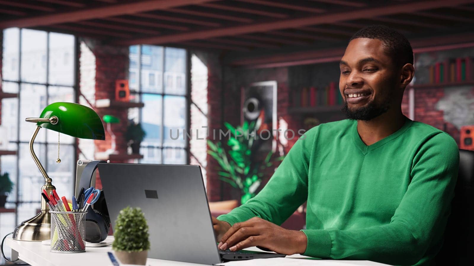 Black teleworker at home desk opening laptop to edit documents and solve daily tasks, updating reports and files. Young employee doing remote job and managing digital paperwork. Camera A.