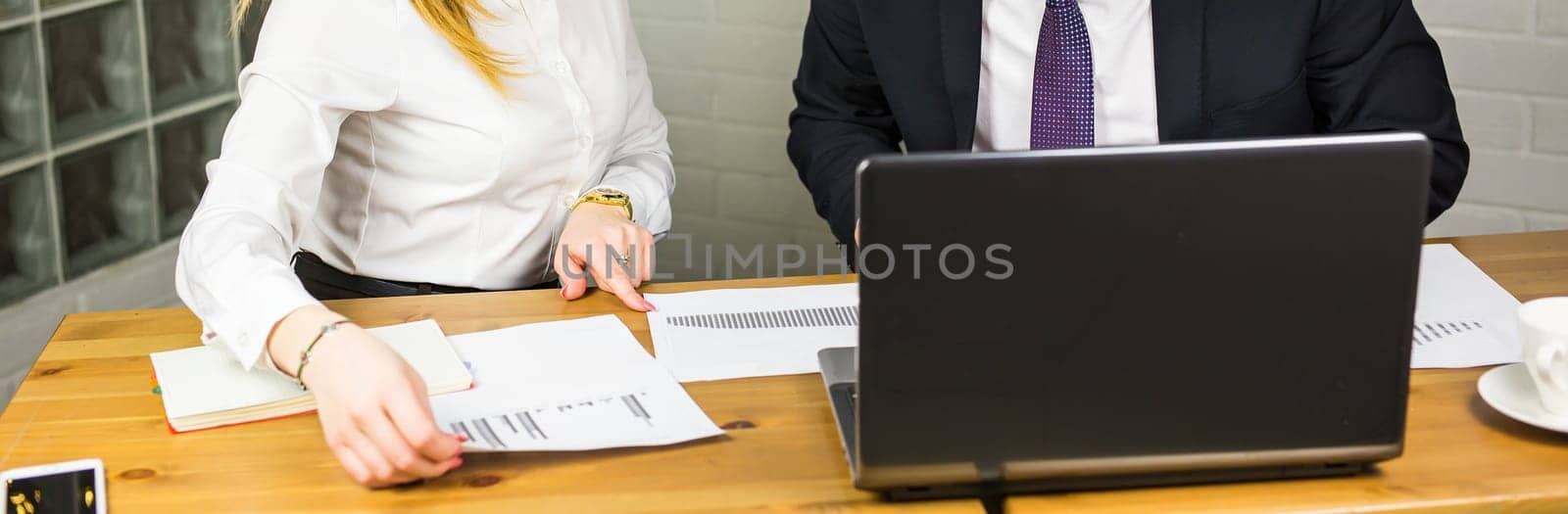 Close-up of smart business partners using laptop at meeting.