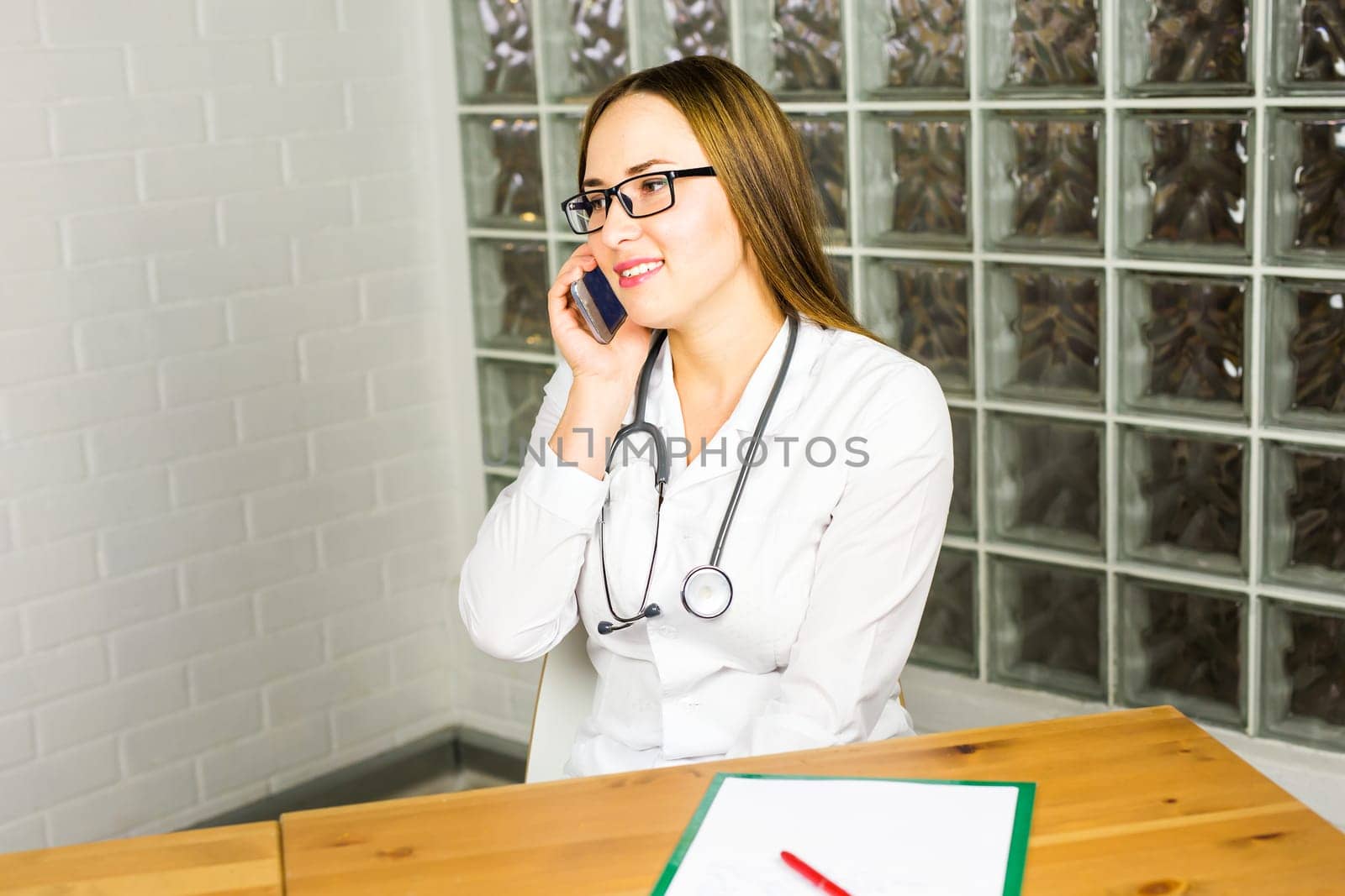 Young beautiful doctor with phone. female medical worker using smartphone.