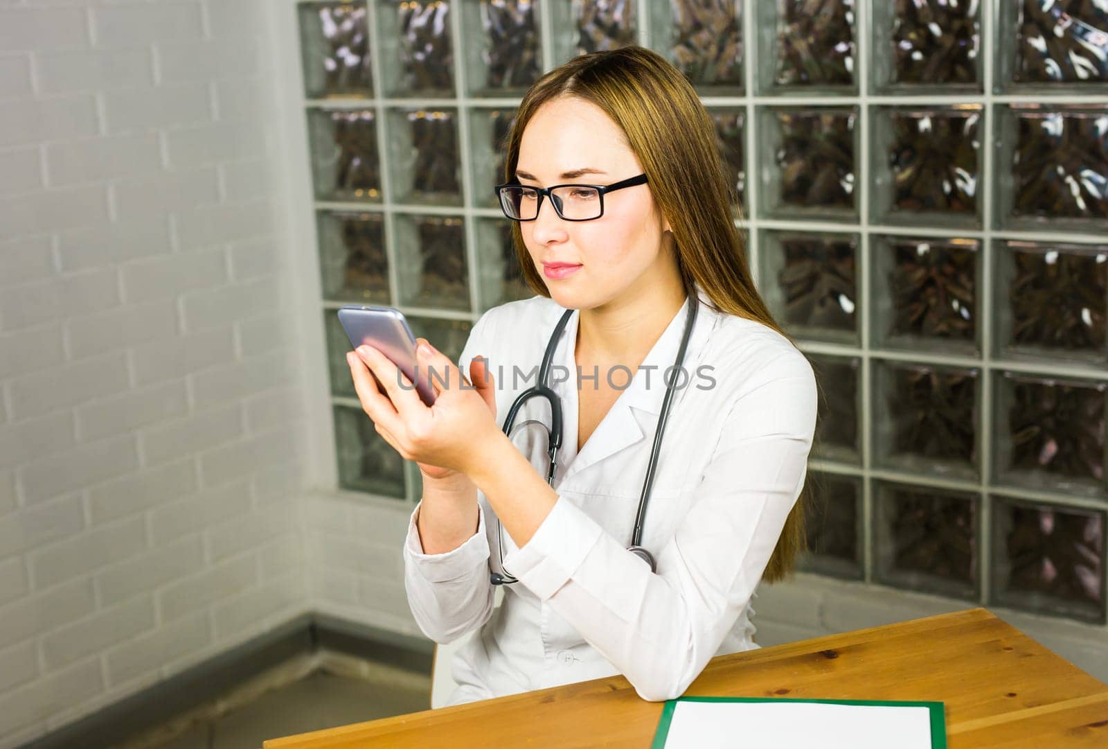 Hands of female medical worker using smartphone.