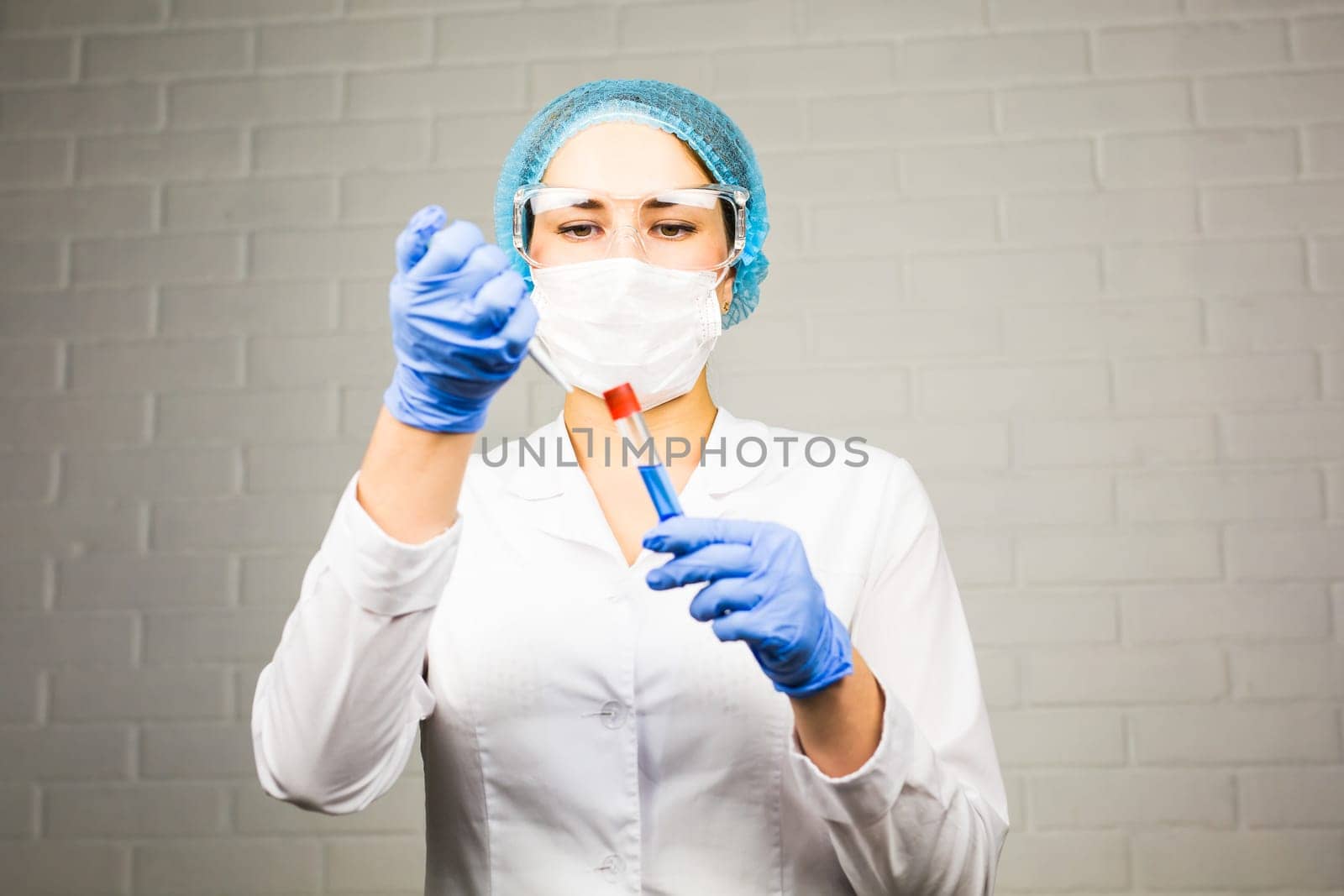 science, chemistry, biology, medicine and people concept - close up of young female scientist holding tube with sample making and test or research in clinical laboratory